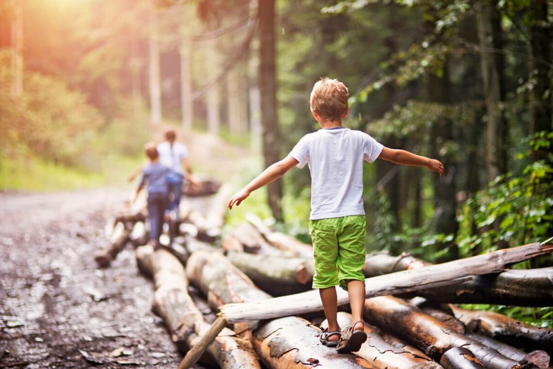 Kinder die auf Baumstämmen laufen